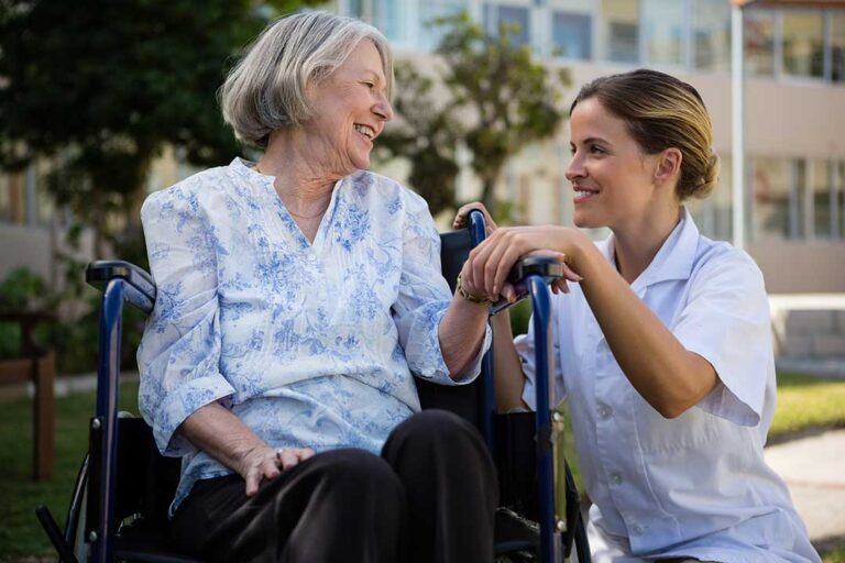 Adult daughter speaking with an assisted living nurse while reviewing a medical folder together.