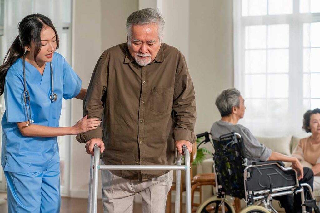 An adult child helps an older woman organize medications at a bright kitchen table.