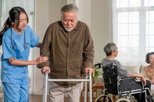 An adult child helps an older woman organize medications at a bright kitchen table.